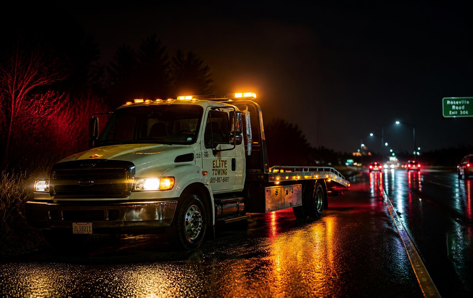 Tow truck with amber warning lights on a wet highway at night